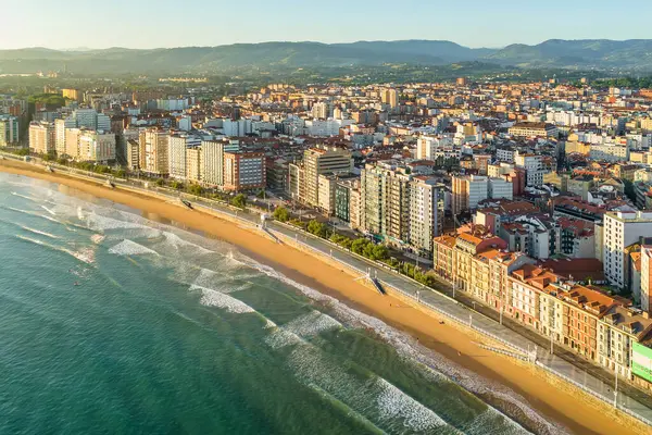Gündoğumunda Gijon 'daki Playa de San Lorenzo plajının havadan görünüşü, Asturias, İspanya. Büyüleyici sahil, Cantabrian Denizi kıyısındaki sahil kasabasının manzaralı manzarasıyla sabah güneşiyle yıkandı.