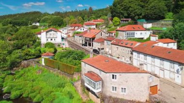 İspanya, Galiçya 'daki Camino de Santiago hac rotasındaki Ponte Maceira köyünün hava manzarası. Tarihi bir Roma köprüsü ve sakin bir kırsal alanda büyüleyici taş evler.