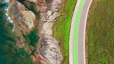 İspanya 'nın Galiçya kentindeki Cantabrian Denizi kıyısının yukarıdan aşağıya havadan görünüşü. Atlantik kıyısında modern bisiklet şeridi olan manzaralı bir sahil yolu.