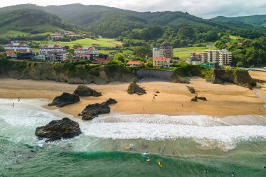 Güzel Bakio Hondartza plajı Bentalde, Bakio, Bask Ülkesi, İspanya. Bir grup sörfçü Kuzey İspanya 'daki çarpıcı kumsalda dalgaları yakalıyor.