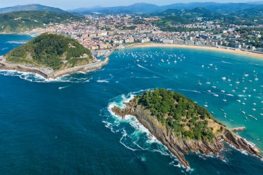Yazın San Sebastian Körfezi 'nin turkuaz sularıyla donostia şehri, Bask Ülkesi, İspanya. Tarihi Santa Klara adası deniz fenerinin üzerinde uçuyor.