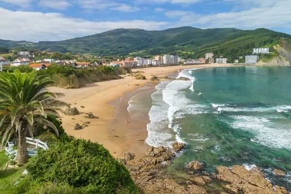 Güzel Bakio Hondartza plajı Bentalde, Bakio, Bask Ülkesi, İspanya. Bir grup sörfçü Kuzey İspanya 'daki çarpıcı kumsalda dalgaları yakalıyor.