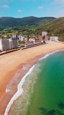 Güzel Bakio Hondartza plajı Bentalde, Bakio, Bask Ülkesi, İspanya. Bir grup sörfçü Kuzey İspanya 'daki çarpıcı kumsalda dalgaları yakalıyor.