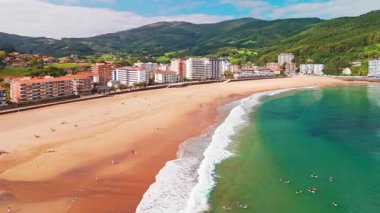 Güzel Bakio Hondartza plajı Bentalde, Bakio, Bask Ülkesi, İspanya. Bir grup sörfçü Kuzey İspanya 'daki çarpıcı kumsalda dalgaları yakalıyor.