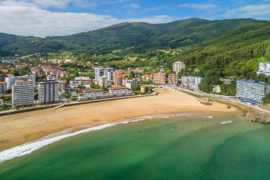 Güzel Bakio Hondartza plajı Bentalde, Bakio, Bask Ülkesi, İspanya. Bir grup sörfçü Kuzey İspanya 'daki çarpıcı kumsalda dalgaları yakalıyor.