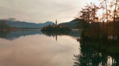 Slovenya 'nın sonbaharda gündoğumunda Bled Gölü' nün havadan görünüşü. Adadaki Hac Kilisesi 'yle manzara manzarası ve dağlarla çevrili ortaçağ Kanlı Kalesi..
