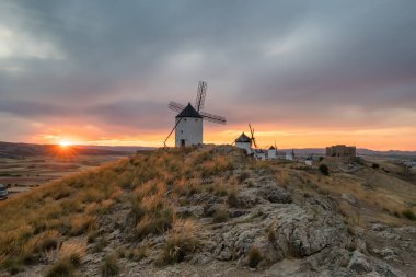 Günbatımında Consuegra 'nın tarihi yel değirmenleri, Castilla-La Mancha, İspanya. Akşam ışığında tepelerde Don Kişot 'un eski tarihi yel değirmenleri. Molinos de Viento de Consuegra