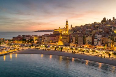 Fransız Rivierası, Fransa 'da Menton' un hava görüntüsü. Muhteşem bir günbatımı, renkli eski kasabanın üzerine sıcak bir ışık saçıyor. Alacakaranlıkta tarihi binalar, plaj ve şehir ışıkları. Fransız Cote dAzur