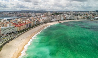 A Coruna, Galiçya, İspanya 'da güneşli bir günde Playa del Orzan plajının hava manzarası. Şehir merkezinde canlı turkuaz deniz suyuyla dolu uzun kumlu bir sahil. Kuzey İspanya 'da halk seyahati