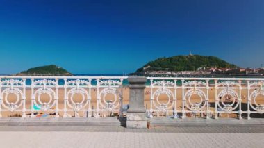 San Sebastian 'da turkuaz suları olan La Concha Sahili ya da Bask Bölgesi, İspanya, Bask Şehri, yaz boyunca. Manzaralı kıyı şeridine bakan ikonik desenli beyaz çitli sinematik manzara.