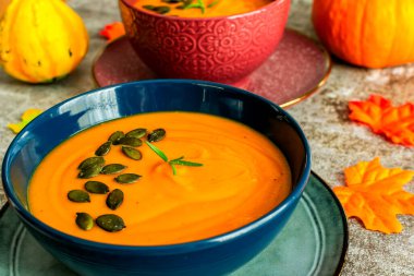 Gri arka planda mavi bir kasede diyet balkabağı çorbası.