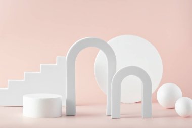 Ürün sunumu için pembe zemin üzerinde çeşitli geometrik şekiller kemerler, toplar, silindir ve merdivenler bulunan soyut bir arkaplan. Kozmetik ürünleri göstermek için podyum.