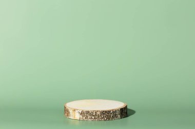 Yuvarlak tahta testere, yeşil arka planda silindir şeklini kesmiş. Minimum kutu ve geometrik podyum. Geometrik şekilli sahne. Eko kozmetik ürün sunumu için boş vitrin