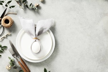 Banner. Stylish Easter flat lay, table setting with egg in easter bunny napkin. Modern natural dyed egg on napkin with bunny ears, flowers on vintage plate. Happy Easter holiday concept for cafes and