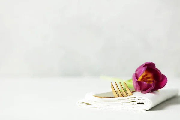 金色のカトラリーセットとテキストのためのスペースとライトグレーのテーブルの上の美しい花 祭りのテーブル設定 — ストック写真