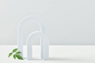 Ürün sunumu için pastel renkli kozmetik sanat deco kemeri görüntüsü. Ürün sunumu için moda geometrik arkaplan ve beyaz arka planda yeşil yapraklar. Asgari şablon podyumunu özetle