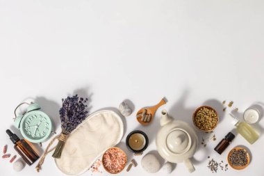 Depresyon ve uykusuzluk tedavisi için bitkisel ilaçlar. Alarm saati, uyku maskesi, şifalı bitkiler, kapsüller, papatya çayı ve aromaterapi yağı beyaz arka planda, üst görünümde, kopyalama alanı