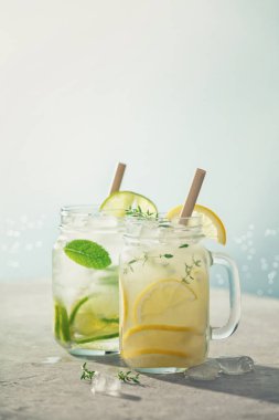 Yaz detoksu ve ferahlatıcı içecekler, limon, nane ve biberiye ile mavi deniz ve gökyüzü arka planında. Güneşli gün gölgeleri