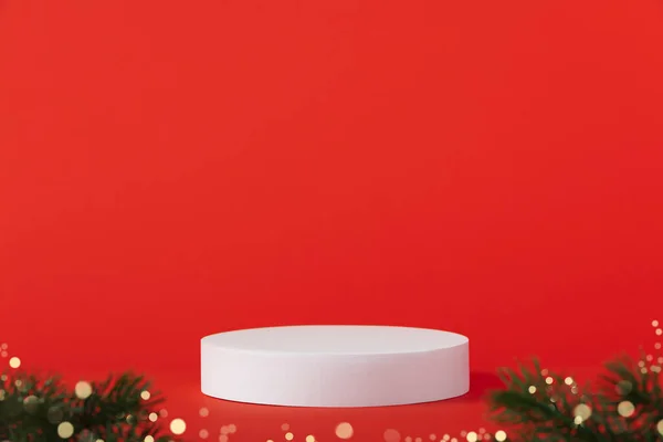 Cosmetic background for Christmas and winter holiday. White podium and christmas decorations on red background.