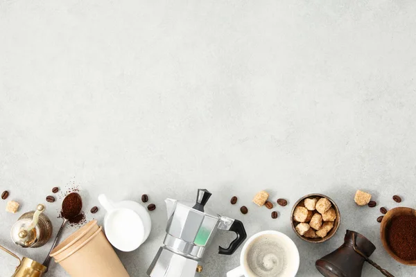 Flat lay with Moka pot, espresso cup, ground coffee, milk, sugar and coffee beans on a grey concrete background. Header with brewing coffee ingredients.