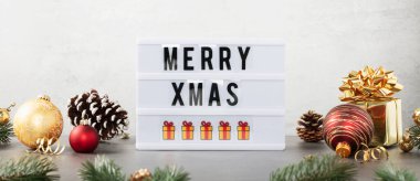 Üzerinde Mutlu Noeller mesajı olan ışık kutusu ve beyaz arka planda duran Noel dekoru. Ön görünüm pankartı