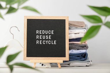 Siyah posta kutusu ve katlanmış kıyafet yığını, küçült, tekrar kullan, geri dönüşüm tırnağı. Sıfır sürdürülebilir yaşam biçimi. Plastiksiz konsept. 