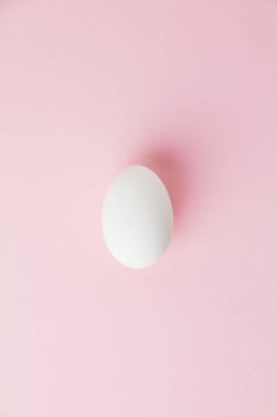 Pastel pembe arka planda beyaz Paskalya yumurtası. Mutlu Paskalyalar. Minimum konsept. Düz yatıyordu. Üst görünüm.