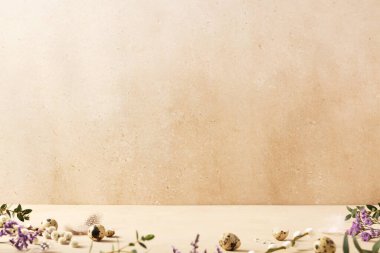 Bej arka planda bıldırcın yumurtası ve bahar çiçekleri olan Paskalya arkaplanı kavramı