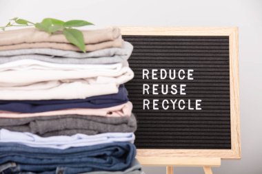 Black letter box and stack of folded clothes, reduce,reuse,recycle quote. Zero waste sustainable lifestyle. Plastic free concept. clipart