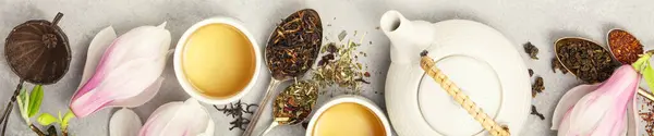 全景展示了不同类型的茶叶和在杯子中酿制的茶 精致的木兰花花为现场增添了春天的新鲜气息 图库图片