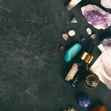 Koyu dokulu yüzeyde gerekli yağ şişesi olan işlenmemiş ve cilalanmış taşlar koleksiyonu meditasyon ve sağIık teması için mükemmel. Boşluğu kopyala