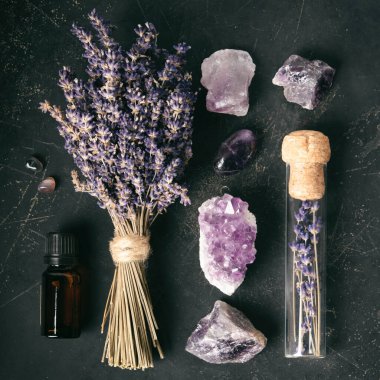 Lavanta filizi, çiğ ametist, mum ve temel yağ koyu dokulu bir yüzey üzerinde meditasyon ve rahatlama için yatıştırıcı bir ortam oluşturur..