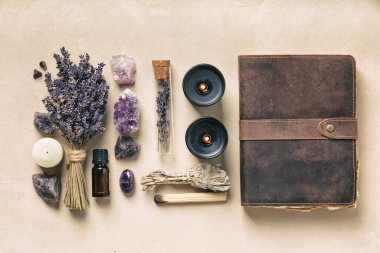 Estetik lavanta, ametist kristaller, mumlar ve deri bir günlük, doğal bir arka planda refahı ve farkındalığı simgeliyor..