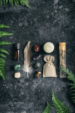 İyileştirici taşlı ve tüylü Aromaterapi ürünleri koyu bir arka planda, bütünsel ve doğal bir yaşam tarzını destekliyor..