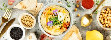 Zeytin yağı, siyah susam tohumu, çam fıstığı, mikroçerez, paprika ve yenebilir çiçeklerle süslenmiş nefis bir kase kremalı humus. Pita ekmeği ve taze malzemelerle servis ediliyor. Mükemmel.
