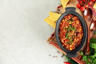 Orijinal Meksika Chili con carne ile servis edilen tortilla cipsi, taze domates, biber ve bitkiler geleneksel mutfak ve canlı gıda konsepti sergileniyor..