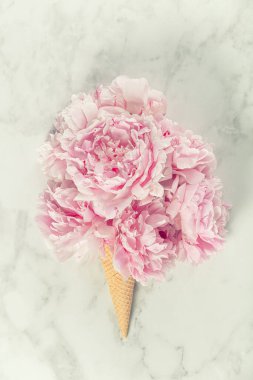 Krep külahında pembe şakayıklardan oluşan yaratıcı bir çiçek aranjmanı mermer bir arka planda..