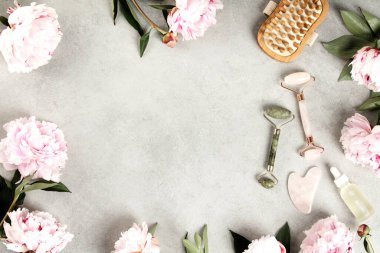 Estetik spa temalı daire, pembe şakayıklar, yeşim taşlı rulo, gerekli yağlar, gua sha, ve bir taş yüzeyde mum. Doğal güzellik ve sağlık konsepti.