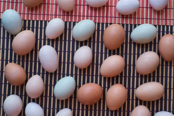 Mutfak masasındaki paspasın üzerinde çeşitli renkte yumurtalar.