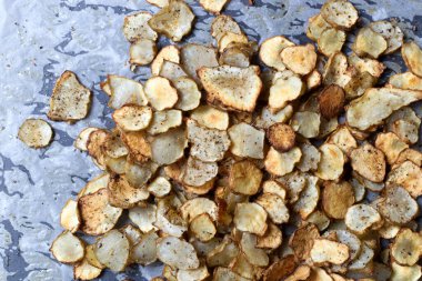 Lezzetli ev yapımı fırınlanmış Kudüs enginar kökü baharatlı sebze cipsi. Parşömen kağıdında eşit olarak sıralanmış. Atıştırmalık seçenekleri için mükemmel sağlık, doku ve lezzet öncelikleri.