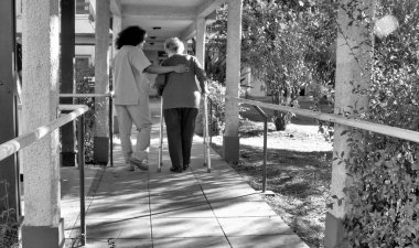 Afrikalı kadın doktor hastane bahçesinde yaşlı, emekli bir kadınla konuşuyor. Mutluluk ve emeklilik kavramı.