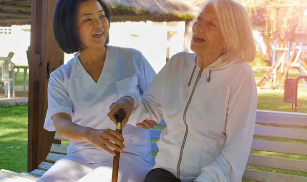Asyalı Doktor Yaşlı Emekli Bir Kadınla Konuşuyor Kisi Bahçe Bankında — Stok fotoğraf