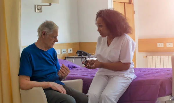 Afrikalı Kadın Doktor Yaşlı Erkek Hastayı Hastane Yatağında Ziyaret Ediyor — Stok fotoğraf
