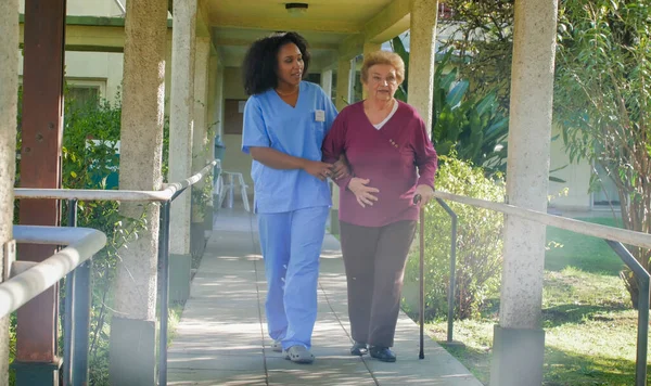 Afrikansk Kvinnlig Läkare Pratar Med Äldre Pensionerad Kvinna Sjukhusgården Lycka Stockbild