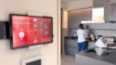 Akıllı ev kavramı. Tablet, modern bir evin içindeki akıllı ev simgelerini ve mutfakta çalışan kadınları gösteriyor..