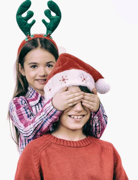 クリスマス家族のシーン 女の赤ちゃんは 彼の兄弟の目をカバー両方の休日服を着た 白で隔離されます — ストック写真