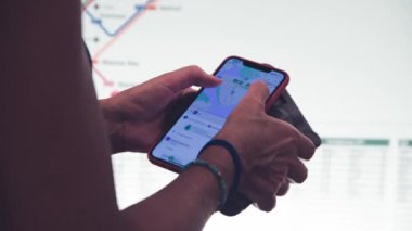 Bir metro istasyonunda varış yerini aramak için akıllı telefon kullanan bir kadın. Turizm konsepti.