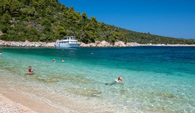 Alonissos, Greece - July 2nd, 2022: Tourists enjoy the beach of Leftos Gialos on a beautiful sunny day.