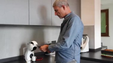 Mutfakta kahve makinesinden bir kupa sıcak filtreli kahve hazırlayan bir adam. Sabahları kahvaltı ediyorum..