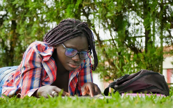 アフリカ系の10代の少女が芝生の上で学校の授業をしている 幸福と軽さの概念 — ストック写真